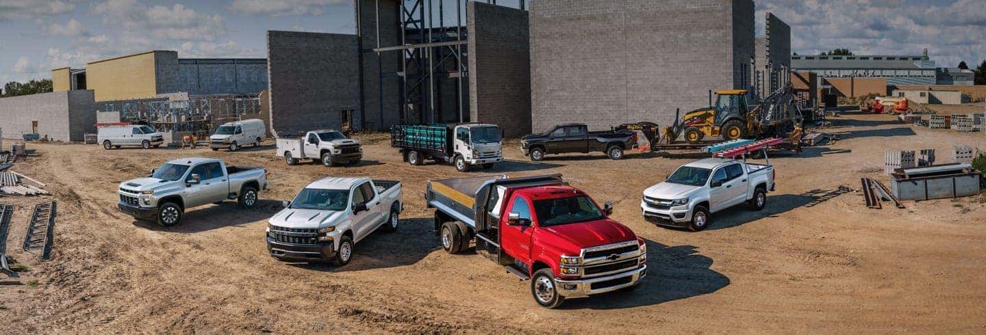 Bunch of trucks in the dirt in front of building