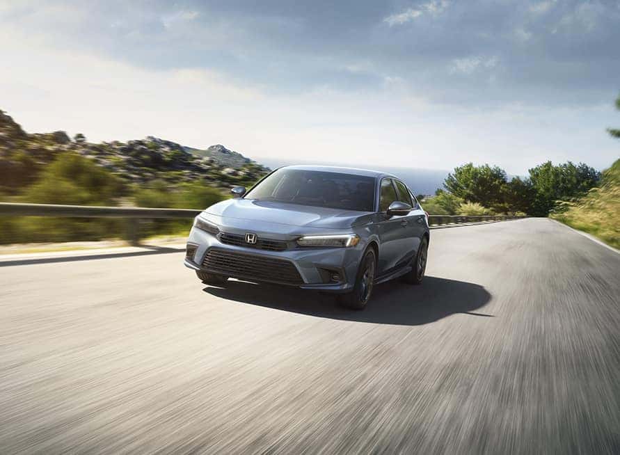 New 2025 Honda Civic at Delaney Honda | 2025 Honda Civic driving up a road during a sunny day