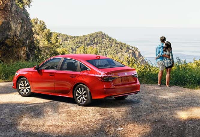 New 2025 Honda Civic at Delaney Honda | Couple hugging together outside while standing in front of their parked 2025 Honda Civic in the color red