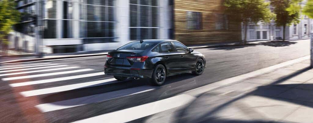 New 2025 Honda Civic at Delaney Honda | Rear profile of a black 2025 Honda Civiv driving down a street