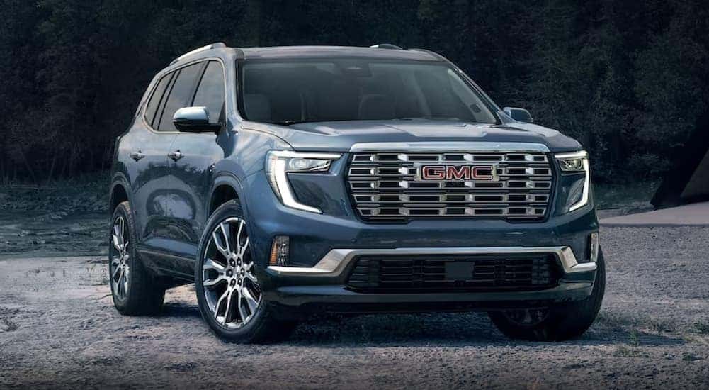 A blue 2024 GMC Acadia Denali is shown parked off-road.