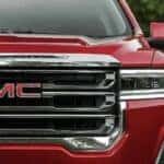 A close up of the grille on a red 2023 GMC Acadia SLT for sale is shown.
