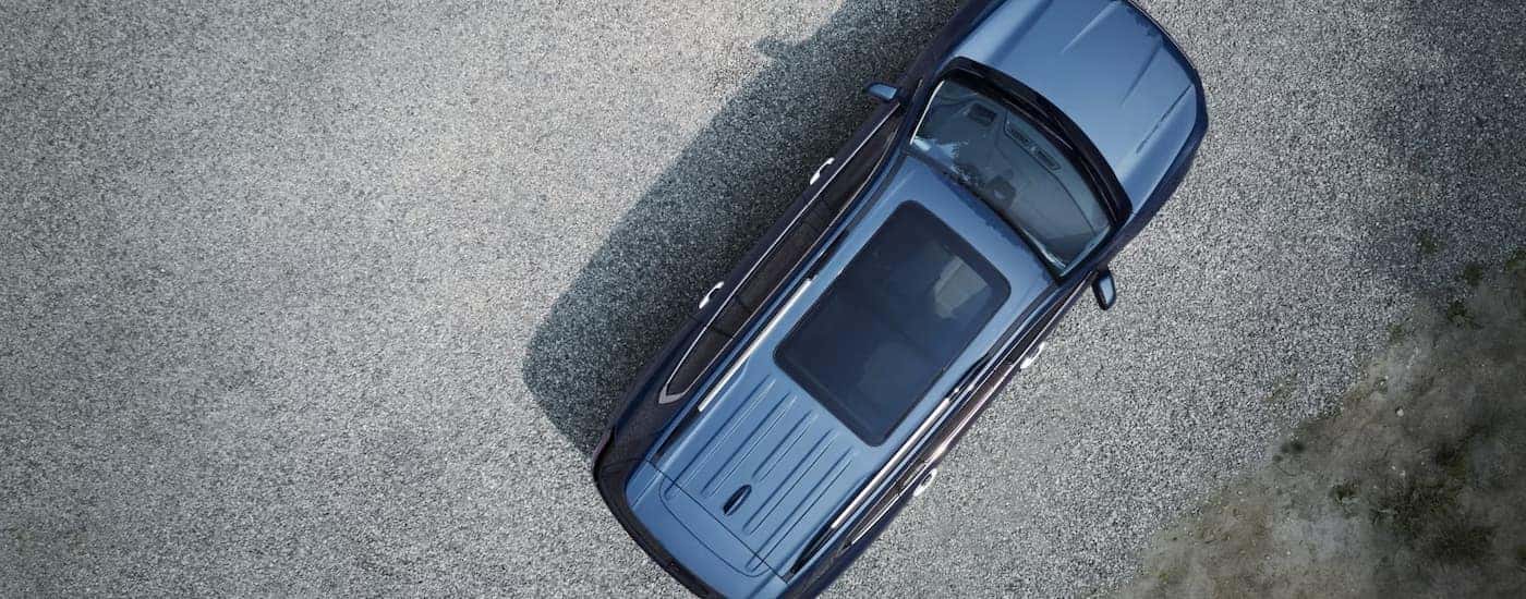 A blue 2024 GMC Acadia Denali is shown from above parked on gravel.
