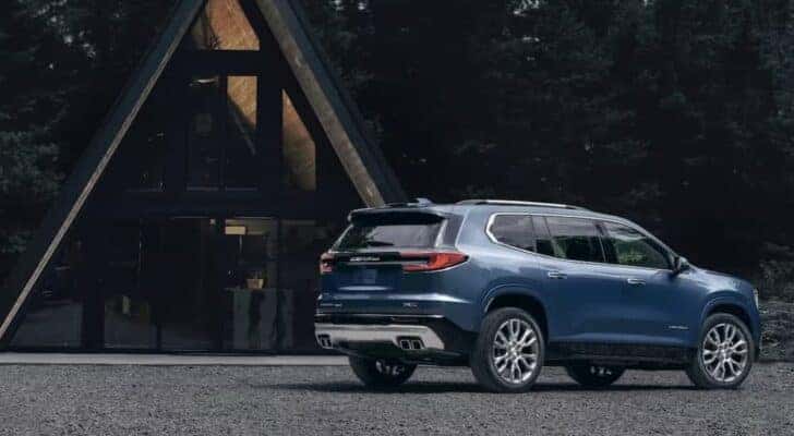 A blue 2024 GMC Acadia Denali is shown parked off-road after visiting a Aurora GMC dealer.