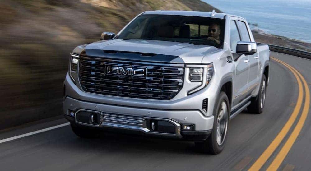 A silver 2024 GMC Sierra 1500 is shown driving on a highway after visiting an Aurora GMC dealer.