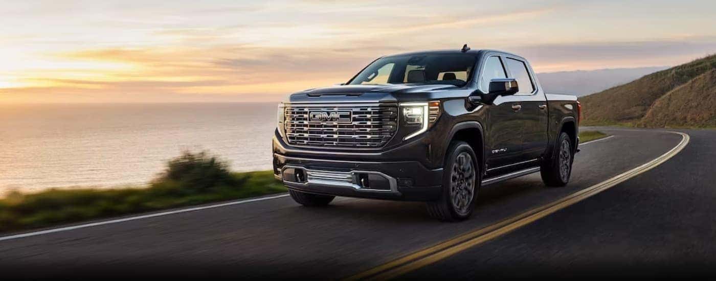 A gray 2024 GMC Sierra 1500 is shown driving on a highway.