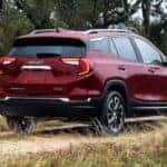 A popular GMC Terrain for sale, a red 2024 GMC Terrain SLE is shown driving on a path.