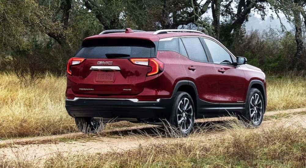 A popular GMC Terrain for sale, a red 2024 GMC Terrain SLE is shown driving on a path.