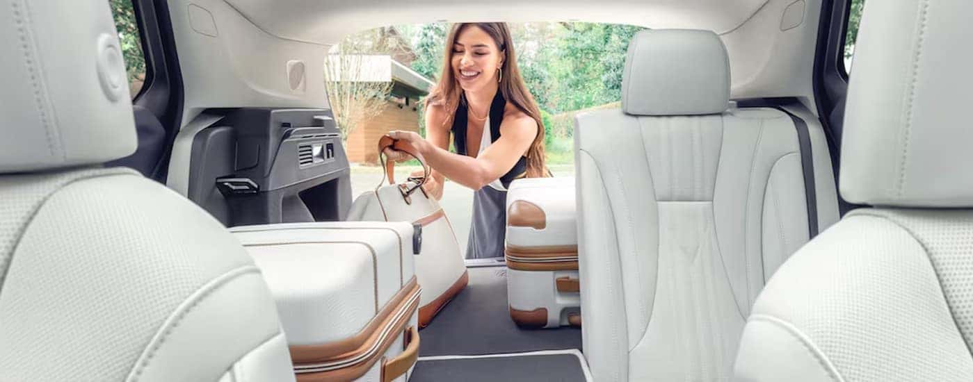 A person is shown placing bags into the rear cargo area in a 2024 Buick Envision.