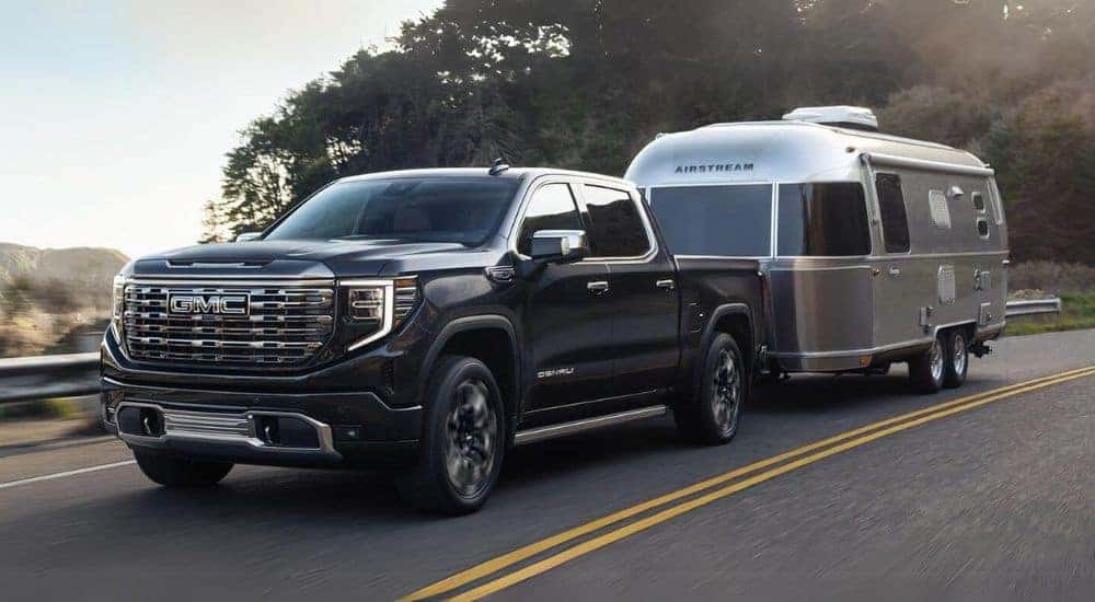A black 2024 GMC Sierra 1500 Denali is shown towing a trailer.