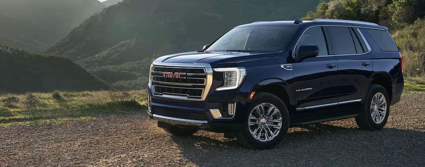 A blue 2024 GMC Yukon XL is shown parked off-road.