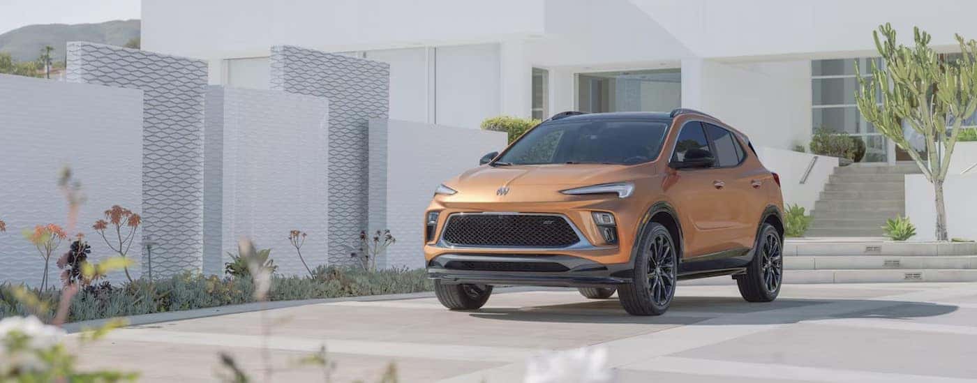 An orange 2024 Buick Encore GX for sale is shown parked on a driveway.