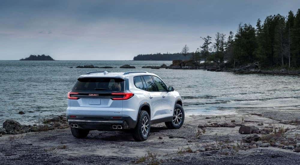 Rear view of a blue 2025 GMC Acadia AT4 parked on a beach.