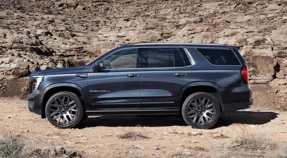 A blue 2025 GMC Yukon Denali is shown parked off-road.