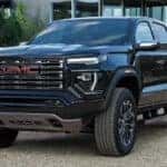 A black 2025 GMC Canyon Denali parked on a driveway.