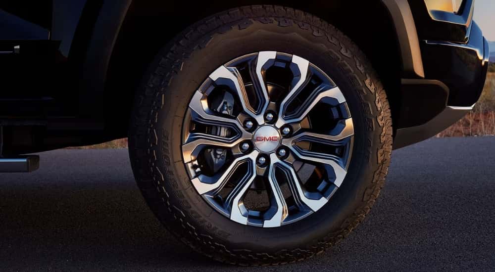 A chrome wheel on a black 2025 GMC Canyon for sale.
