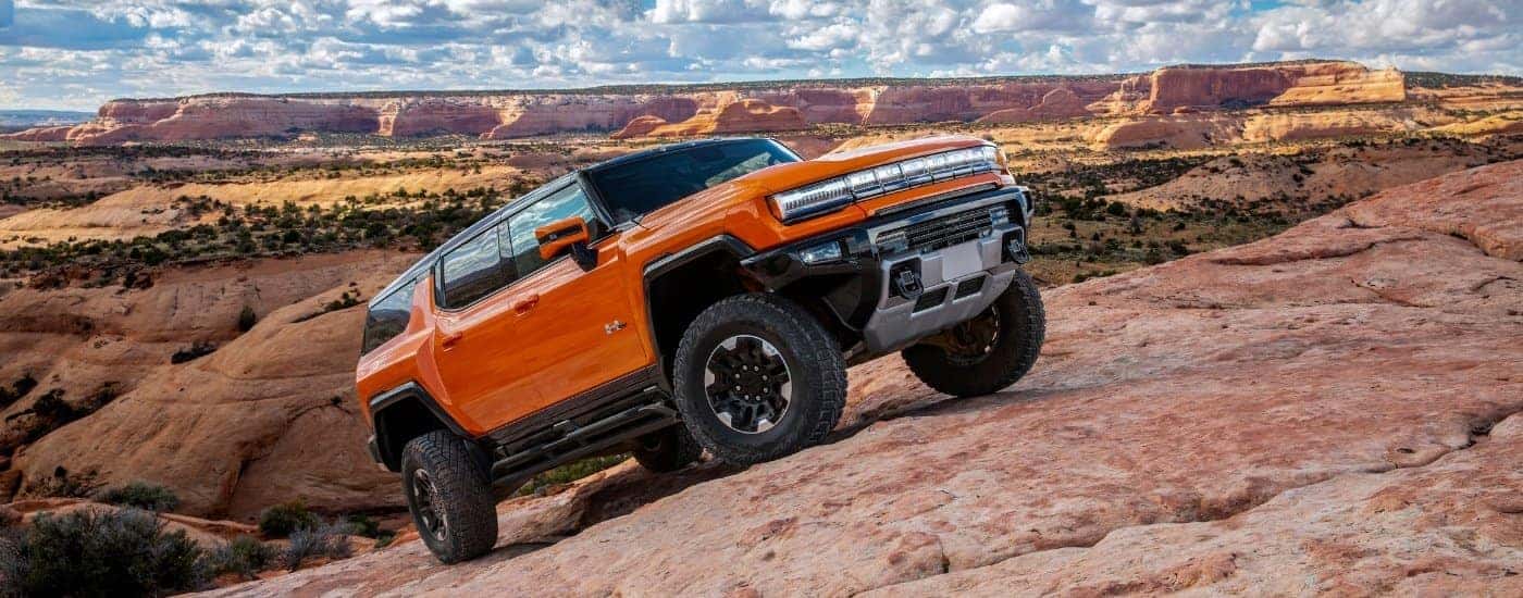 An orange 2025 GMC Hummer EV off-roading.