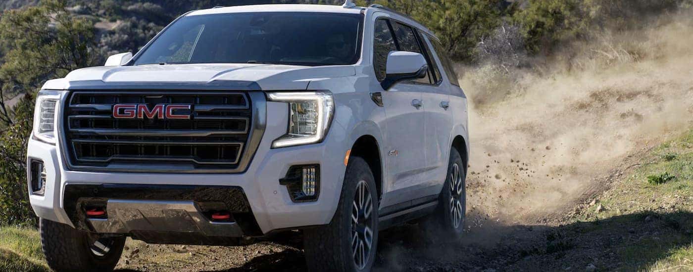 A white used 2023 GMC Yukon AT4 driving off-road