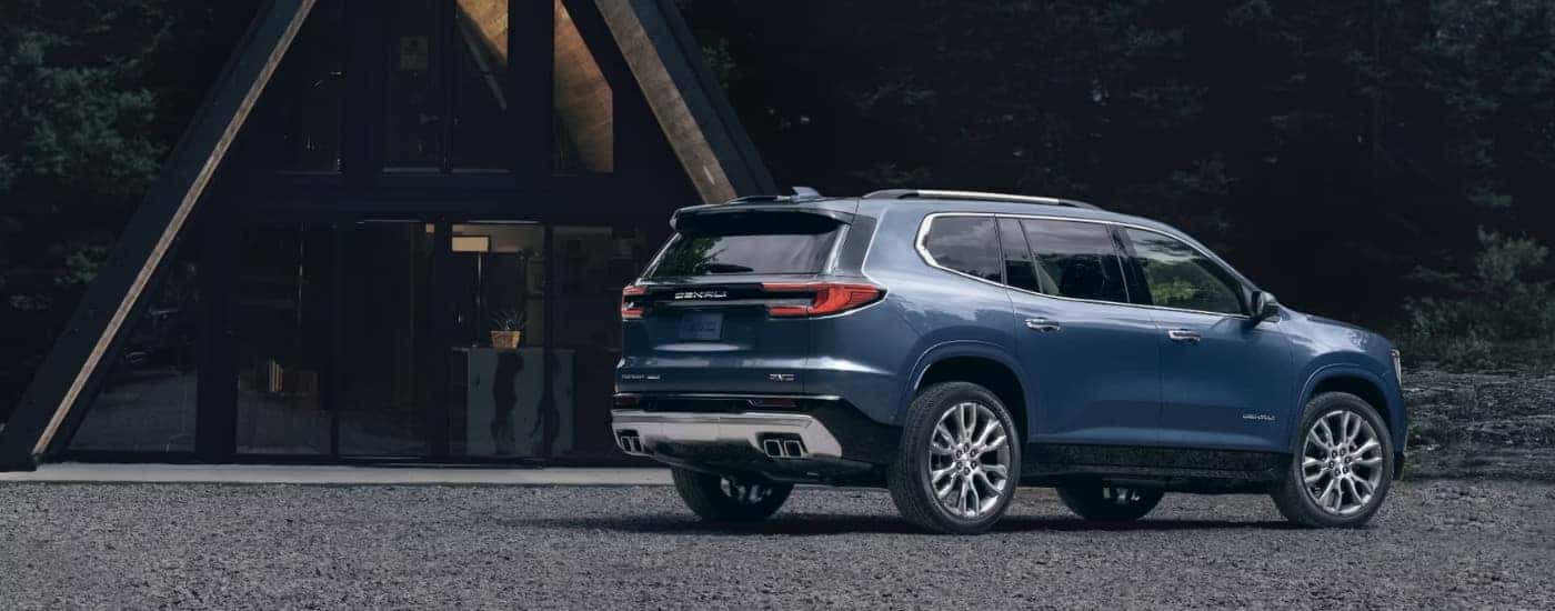 A blue 2024 GMC Acadia Denali is shown parked off-road after visiting a Aurora GMC dealer.