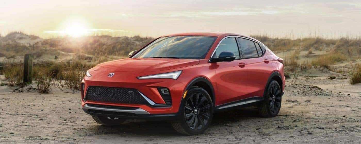 A red 2024 Buick Envista ST is shown parked on sand after visiting a Buick dealer.
