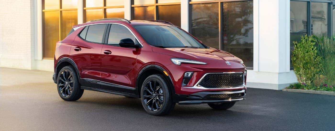 A red 2024 Buick Encore GX ST is shown parked near a white building.