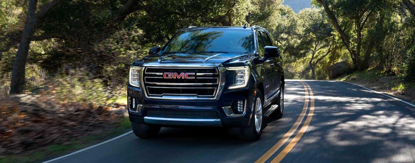 A black 2023 GMC Yukon XL is shown driving on a highway.