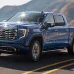 Blue 2025 GMC Sierra 1500 for sale driving down a road.