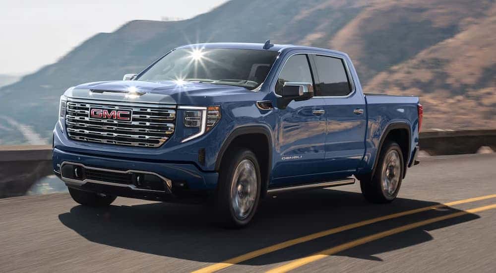 Blue 2025 GMC Sierra 1500 for sale driving down a road.