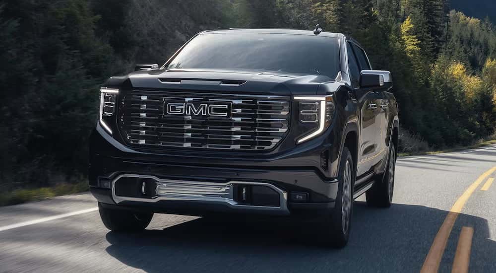 Black 2025 GMC Sierra 1500 Denali Ultimate driving around a bend.