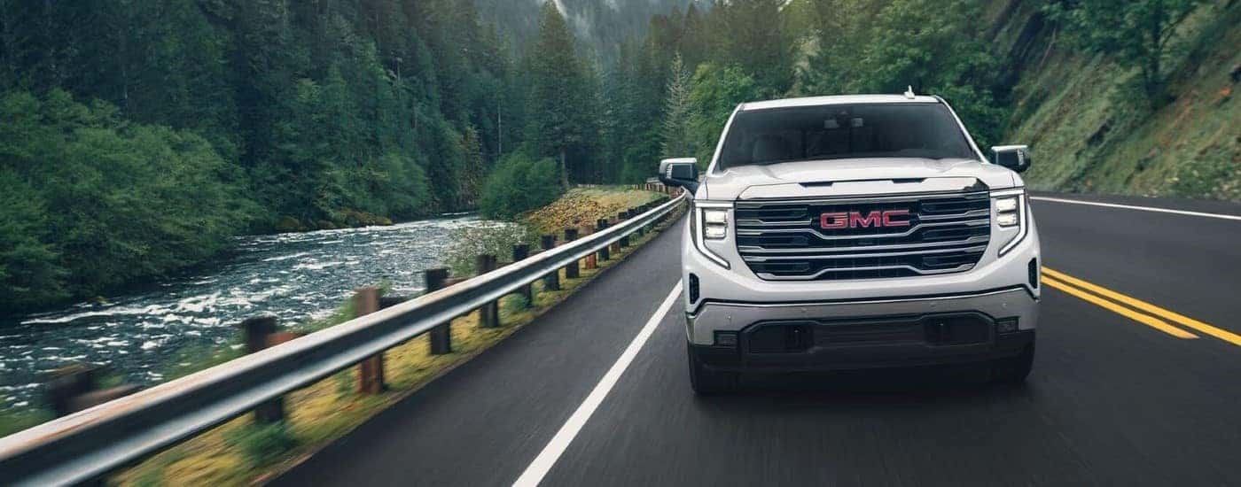 A white 2024 GMC Sierra 1500 for sale near Elgin driving on a highway.