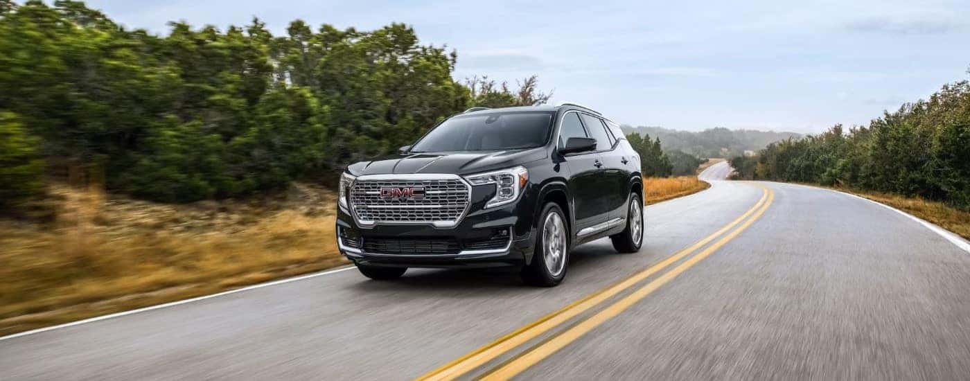 A popular GMC Terrain for sale, a black 2023 GMC Terrain Denali, is shown driving on a highway.