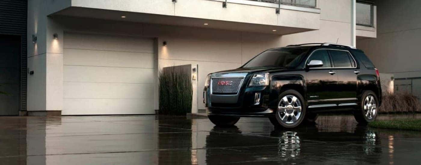 A black 2015 GMC Terrain parked on a wet driveway.