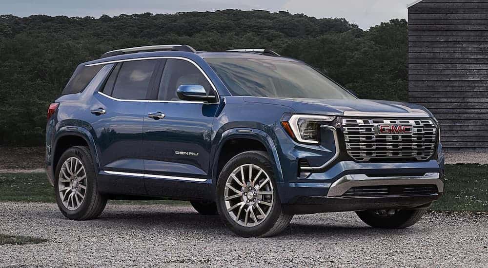 Blue 2026 GMC Terrain Denali parked on gravel.