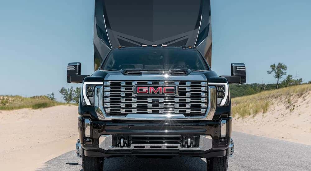 A black GMC Sierra 2500 HD Denali towing a camper