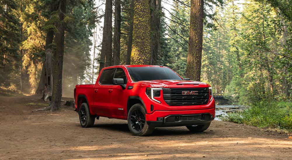 Red 2026 GMC Sierra 1500 parked off-road near a tree.