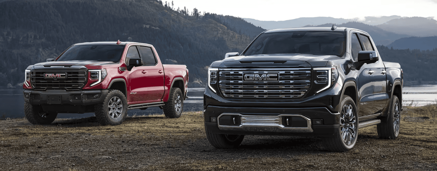 A red 2026 GMC Sierra 1500 At4 parked next to a black 2026 GMC Sierra 1500 Denali
