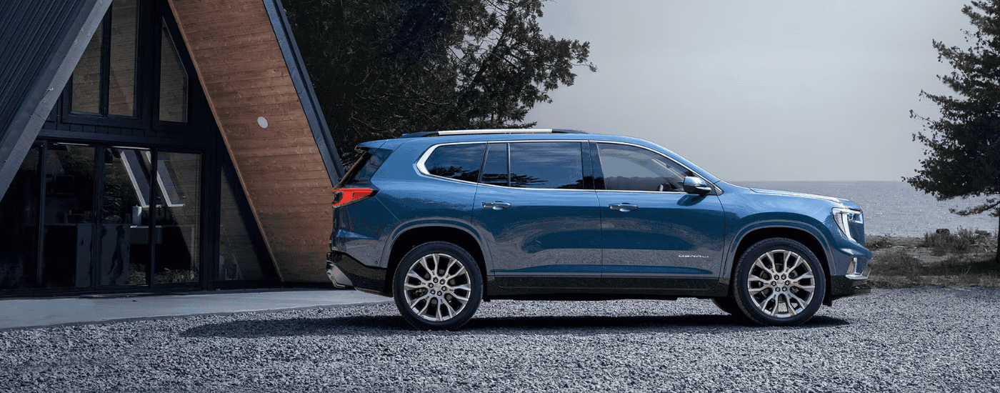 Blue 2026 GMC Acadia parked in front of a house
