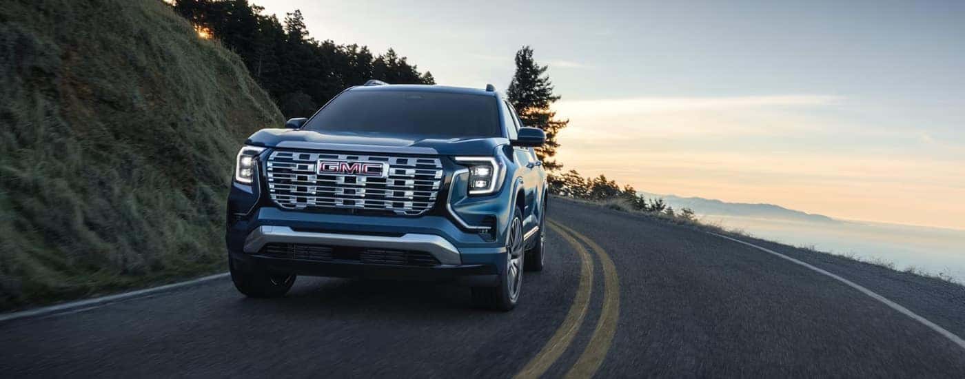 Blue 2026 GMC Terrain Denali rounding a bend