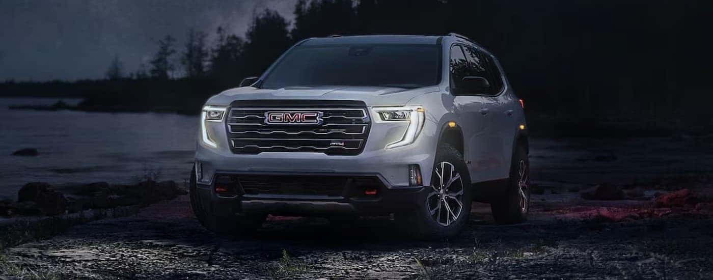 A white 2024 GMC Acadia AT4 parked at night.