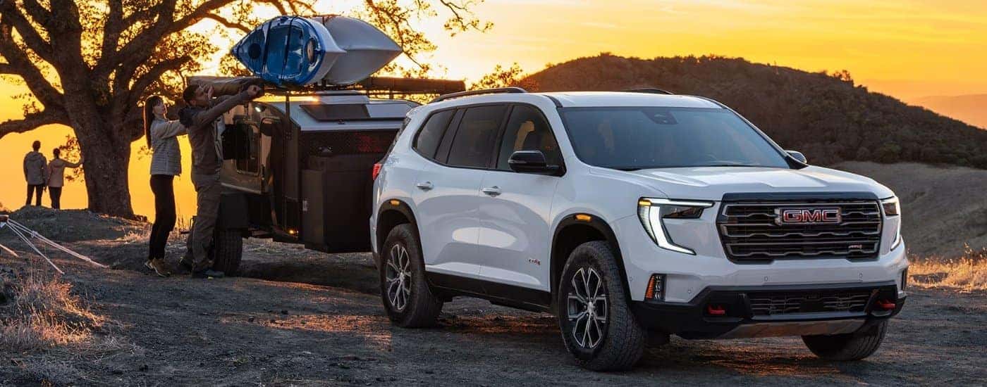 White 2026 GMC Acadia AT4 with a trailer parked off-road