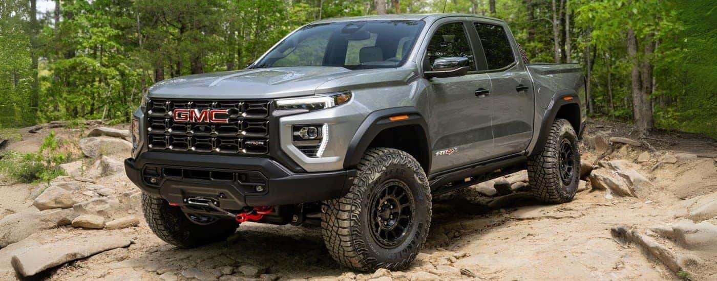 A silver 2025 GMC Canyon AT4X AEV driving off-road.