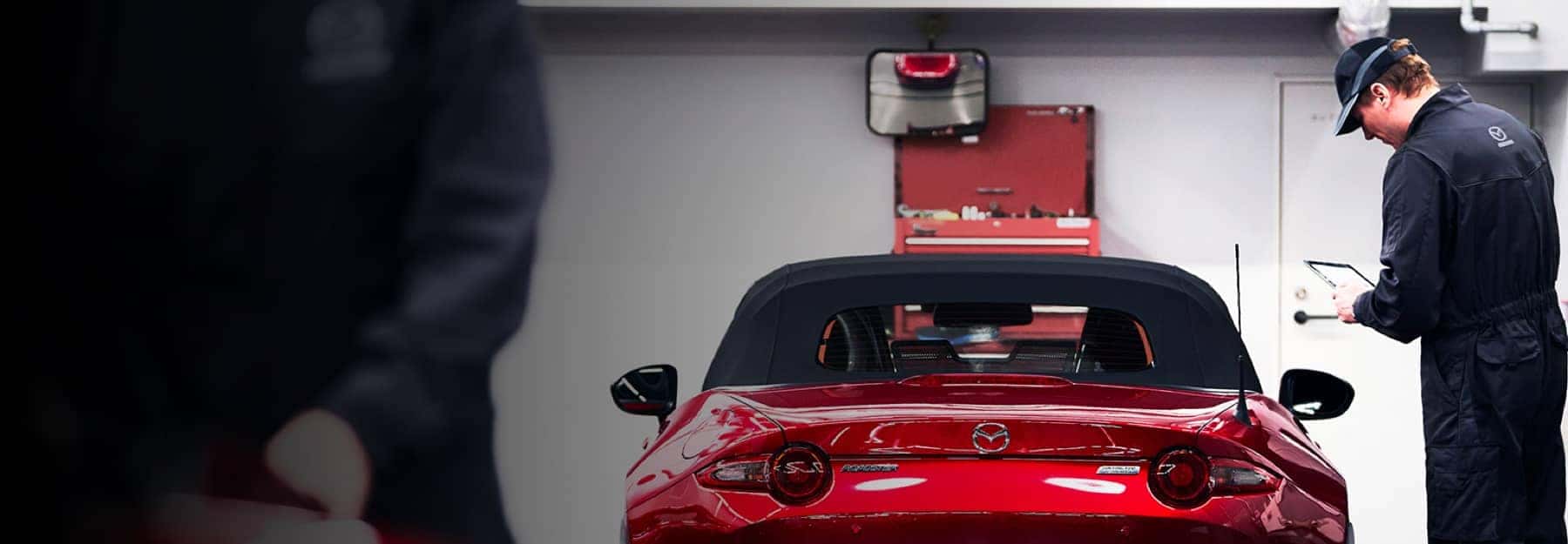 service technician working on red Mazda