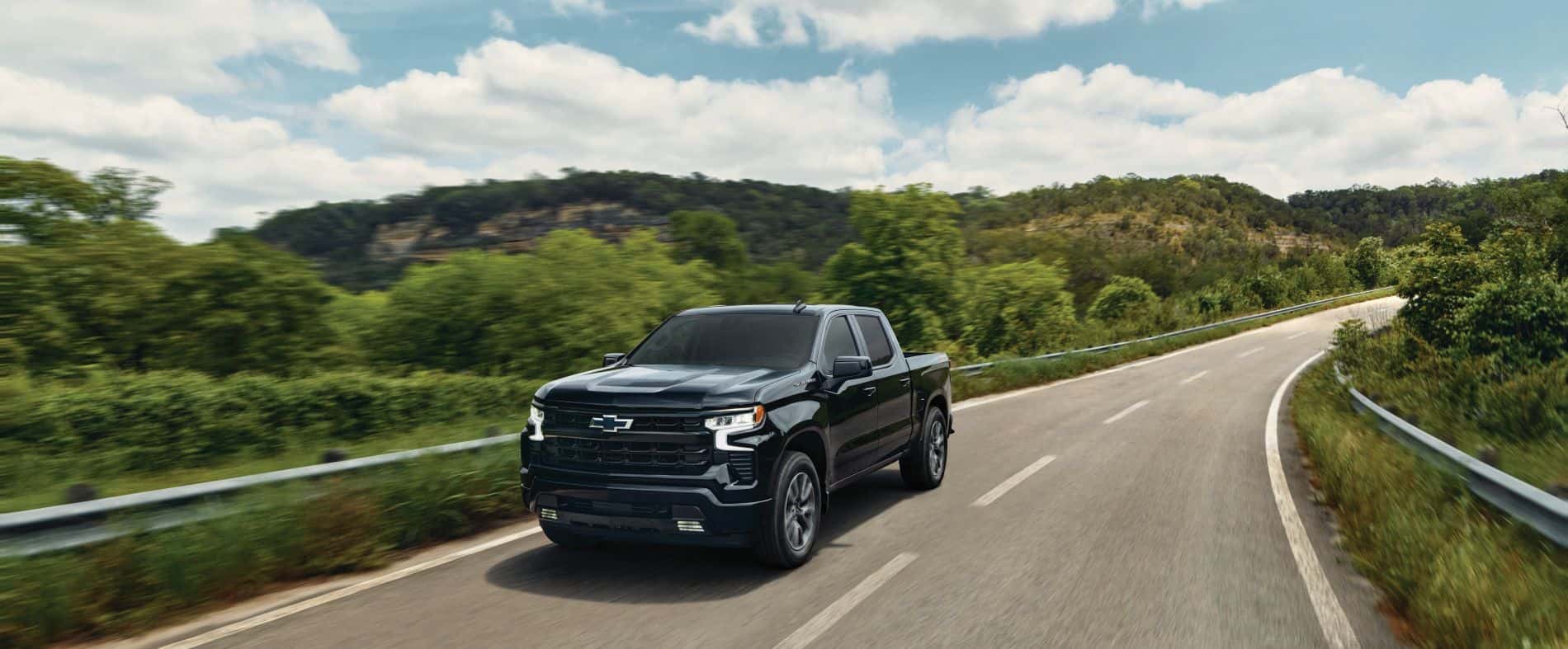 2026 Silverado 1500 RST driving down the open summer road.