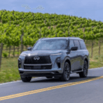 Redesigned INFINITI QX80 driving down highway on summer day