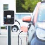Electric car plugged in at public electric vehicle charging station.