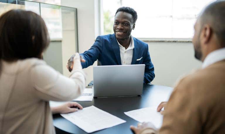 Customer shaking hands with car salesman buying a car