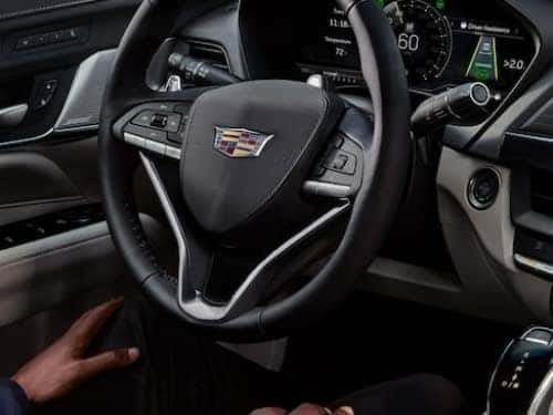 2024 Cadillac CT4 close up view of driver infotainment screen showing super cruise and man in driver seat with hands on his lap