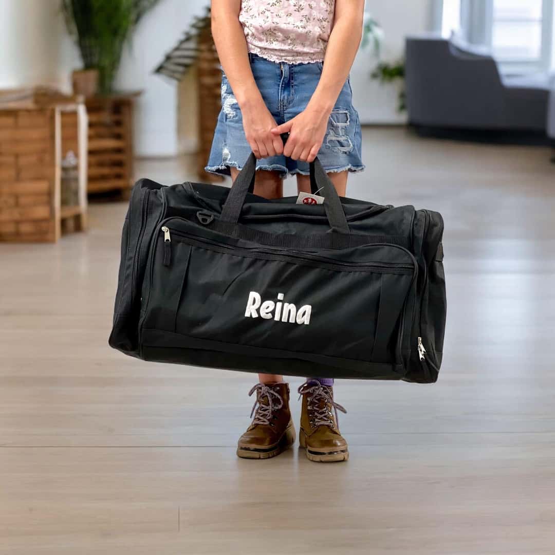 Young girl smiling as she holds a Bag of Hope duffel bag