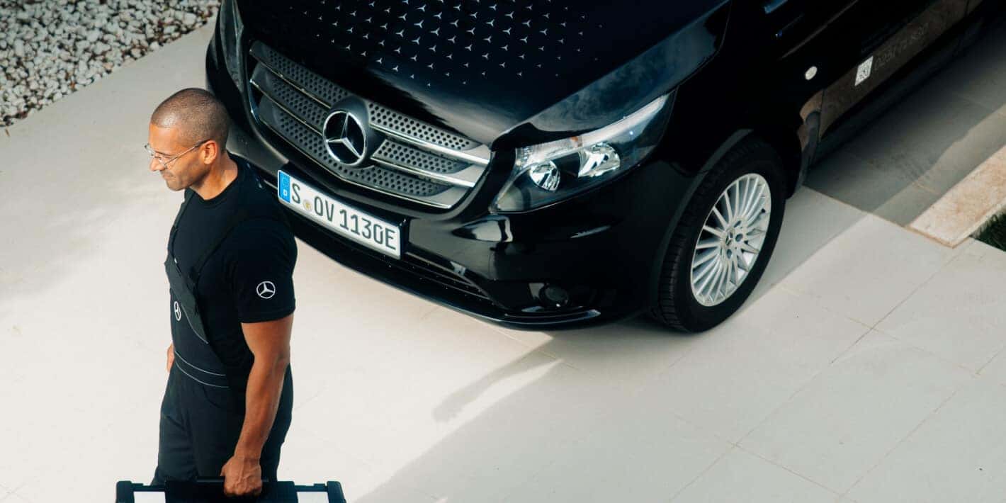 Mercedes-Benz Cargo Van parks on a driveway while a technician walks past.