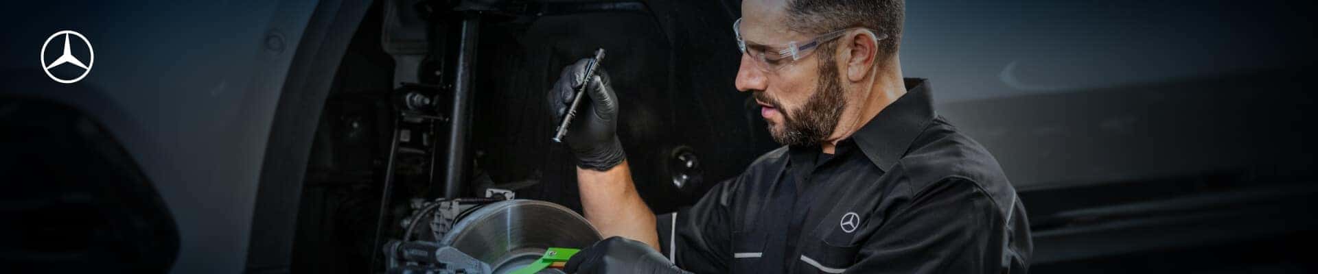 A Mercedes-Benz Certified Technician inspects the brakes on an exposed Mercedes rotor.